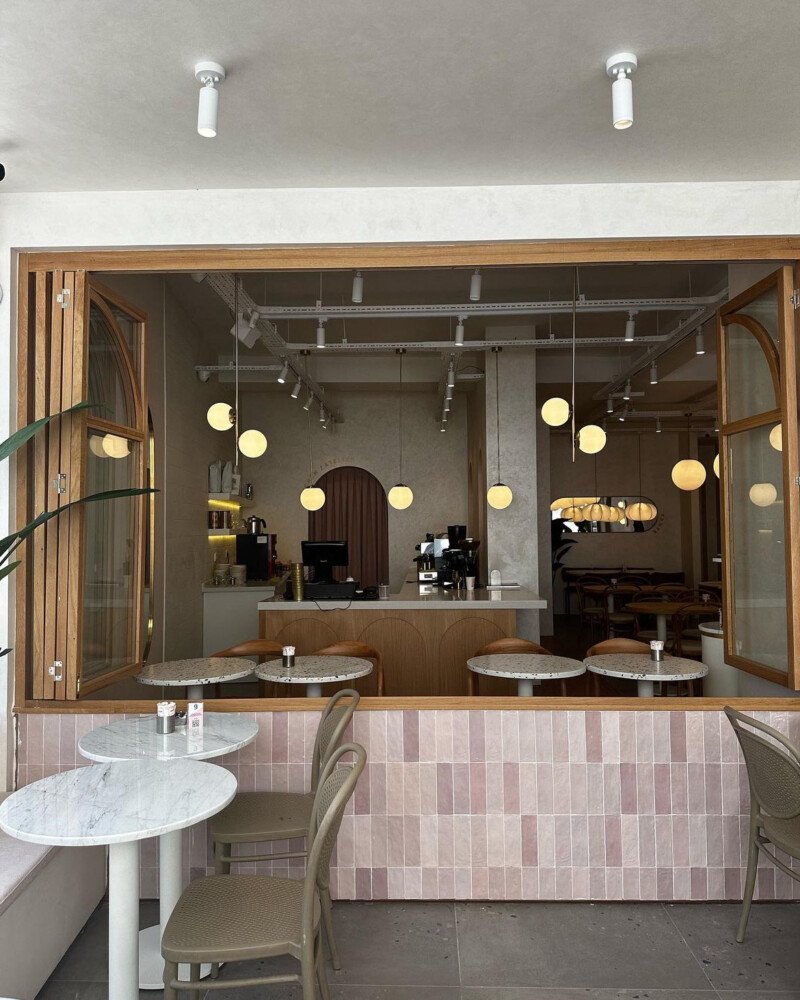 Ameublement pour café professionel Café-restaurant décoré en rose, avec des tables en marbre ou terrazzo à pieds blancs et des chaises