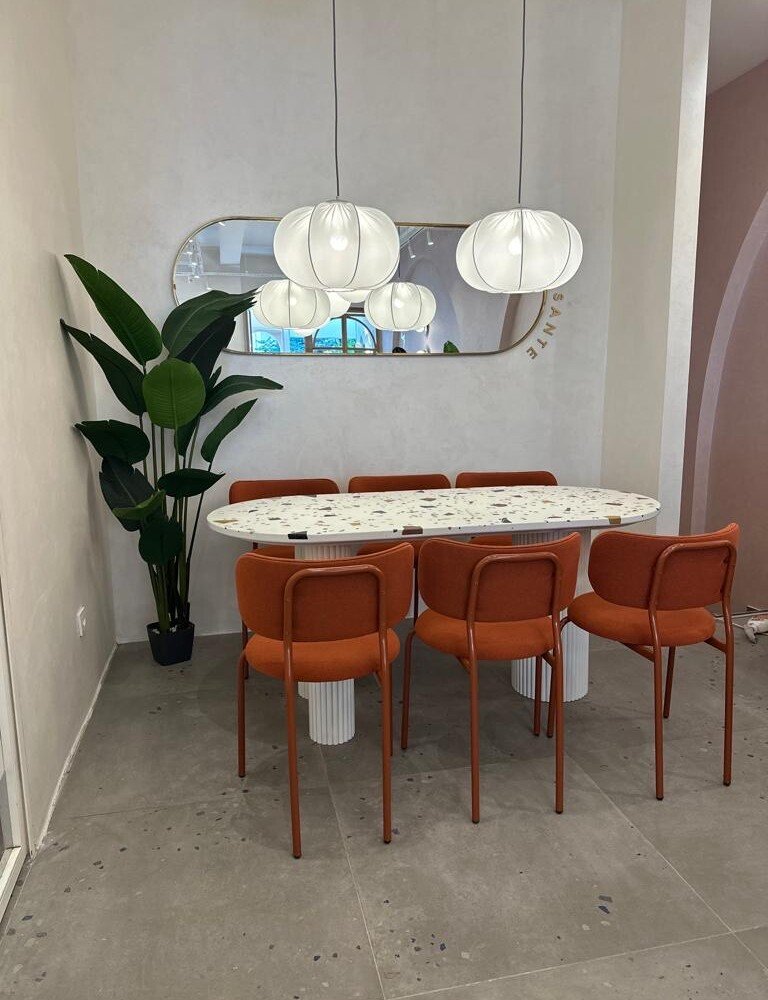 Ameublement professionnel : table en terrazzo avec pieds blanc, accompagnée de chaises orange, design moderne et convivial