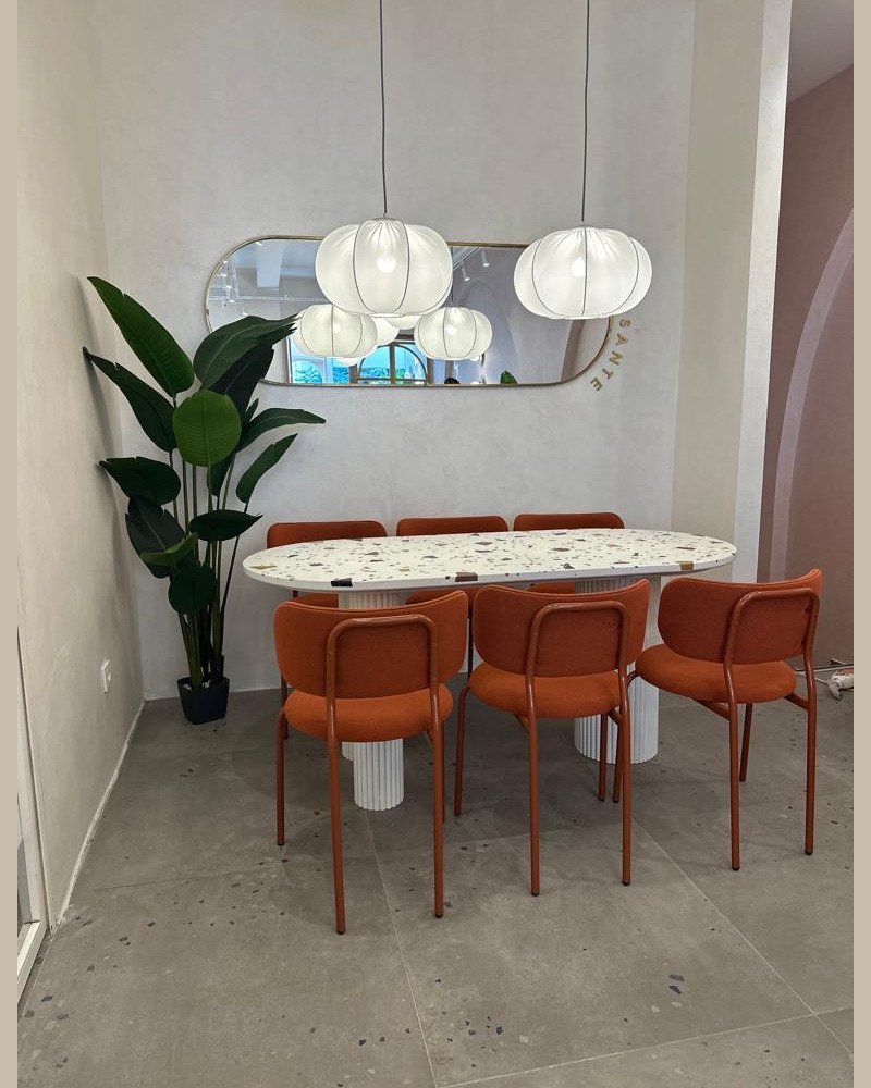 Ameublement professionnel : table en terrazzo avec pieds blanc, accompagnée de chaises orange, design moderne et convivial