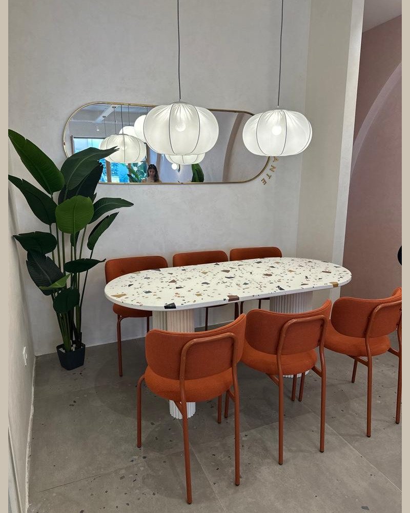 Ameublement professionnel : table en terrazzo avec pieds blanc, accompagnée de chaises orange, design moderne et coloré
