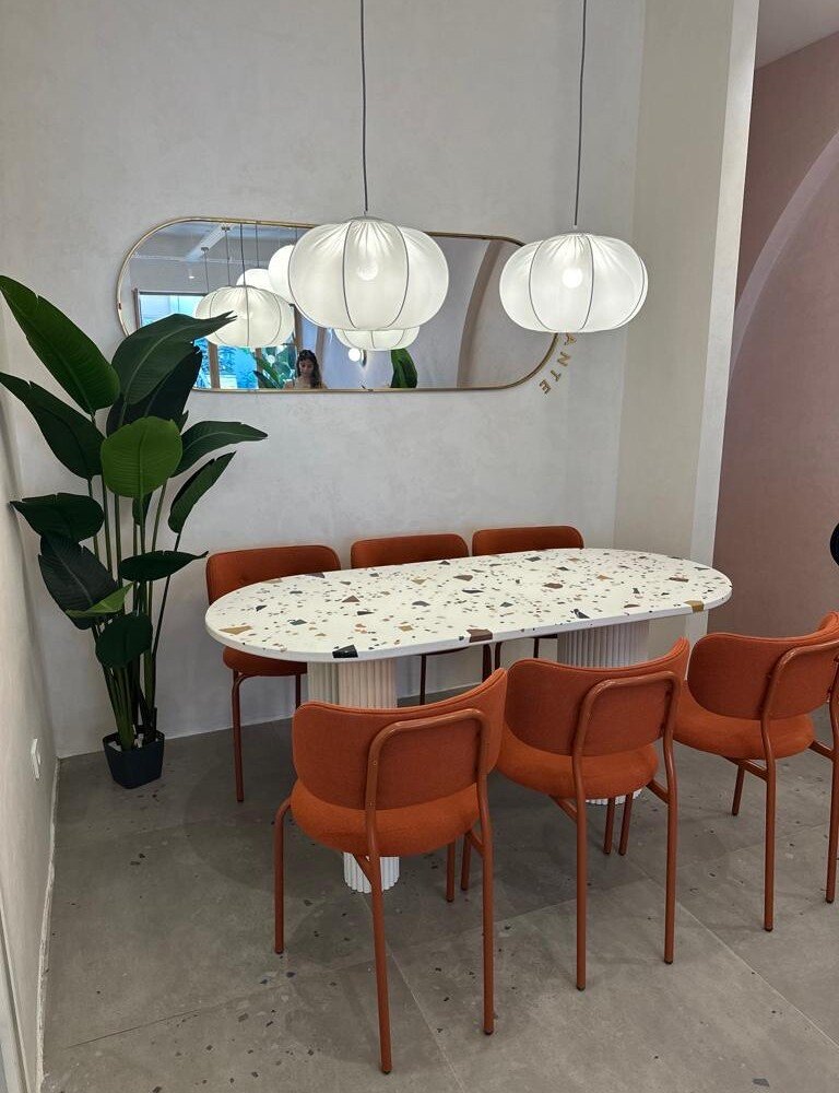 Ameublement professionnel : table en terrazzo avec pieds blanc, accompagnée de chaises orange, design moderne et coloré