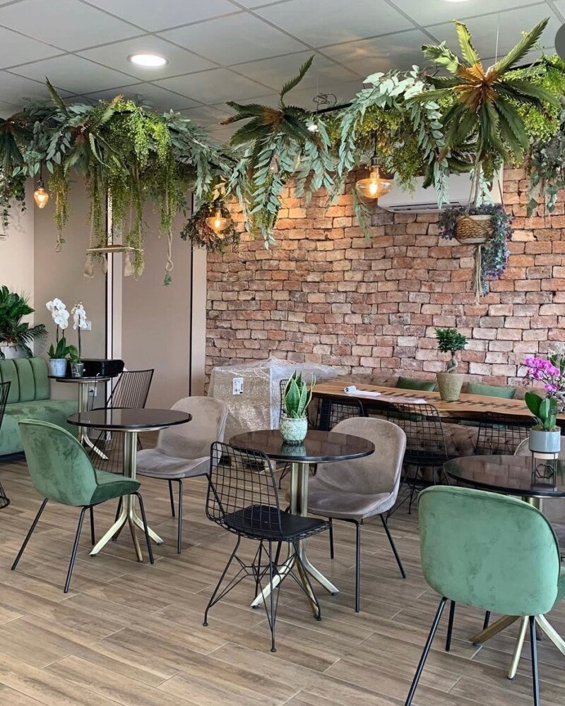 Café avec tables et chaises vertes en métal noir, ambiance moderne pour un café